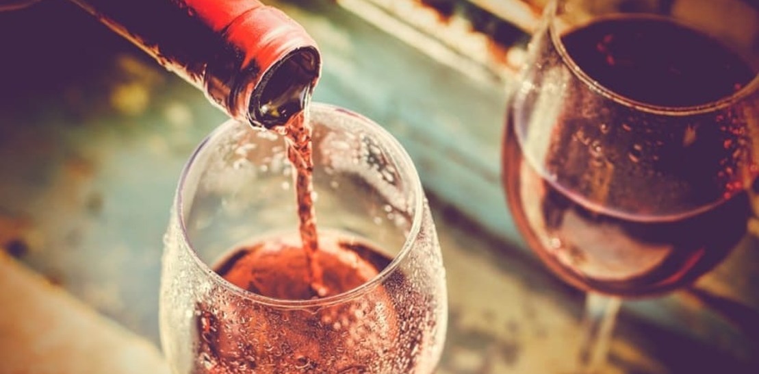 Бокалы и бутылка с льющимся вином